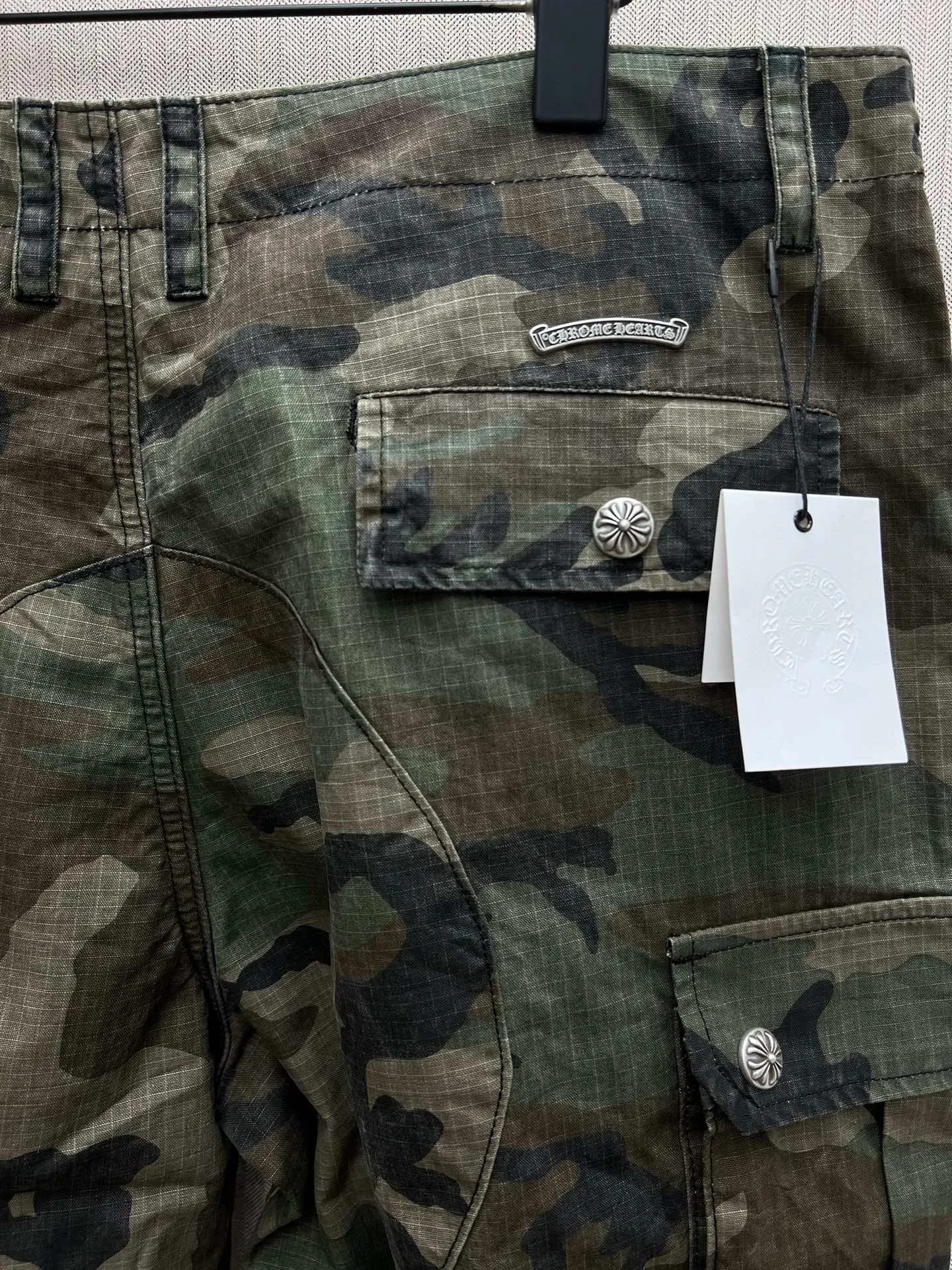 🅿️680 Crow Heart 25SS camouflage patchwork leather genuine antique silver overalls. The body fabric is custom-dyed with fully divided camouflage. The lining is CH jacquard lining. The minimum order is 1000 meters. There are 14 genuine antique silver hardware in the whole trousers. Half of the cost is in the hardware. The leather patchwork is made of imported lambskin. Hand-made edge turning method. The embroidery on the waist is imported Tajima machine. Precision embroidery. Size: 32.34.36